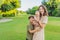 A happy 40-year-old mother cradles her newborn with her adult son in a sun-drenched park. Love, family and generations