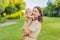 A happy 40-year-old mother cradles her newborn in a sun-drenched park. Love, family and generations in harmony