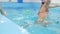 Happy 5 years old girl is jumping at individual swimming lesson with a male personal trainer in pool in swimming cap and