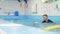 Happy 5 years old girl is jumping at individual swimming lesson with a male personal trainer in pool in swimming cap and