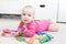 Happy 6 month baby girl plays wooden multicolored meccano