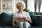 Happy 60s grandmother relax on couch doing knitting
