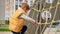 Happy active boy playing on the public playground and climbing up high using ropes and nets. Active child, sports and development