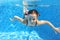 Happy active child swims underwater in pool