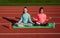 Happy active children meditate sitting in lotus position on yoga mat athletics track, meditation