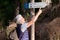 Happy and active elderly man leaving for a hike in the woods. Backpack and casual wear. Indicates the way to go