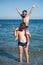 Happy active funny sport little boy sitting on thick child in diving mask shoulders standing on summer sea sunny beach during