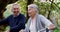 Happy, active and retired senior couple enjoying a walk with their bicycles through a park while laughing and having fun