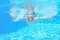 Happy active underwater child swims in pool