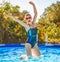 Happy active woman in blue swimwear in swimming pool jumping