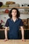 Happy adolescent guy in dark blue shirt standing by wooden table in garage