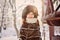 Happy adorable child girl in fur hat and coat near bird feeder on the walk in winter forest