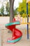 Happy adorable child girl on swing on playground near kindergarten Montessori on summer day