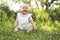 Happy adorable chubby baby girl sitting on the grass