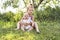 Happy adorable chubby baby girl sitting on the grass with her daughter sister