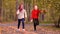 Happy adorable girls running with leaf bouquets in autumn park in slow motion