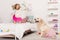happy adorable kid jumping on bed, golden retriever sitting on carpet in pink skirt