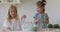 Happy adorable kids sisters enjoying cooking together preparing dough