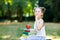 Happy adorable little kid girl reading book and holding different colorful books, apples and glasses on first day to