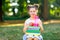 Happy adorable little kid girl reading book and holding different colorful books, apples and water bottle on first day