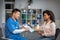 Happy adult chinese man doctor showing contract to young african american female patient in clinic