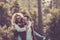 Happy adult couple enjoy nature wood forest together and outdoor leisure activity with fun and joyful - man carry woman on his