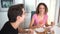 Happy adult couple speaking while sitting at dining table and eating breakfast