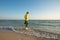 Happy adventurer is walking along the surf line and smiling