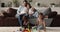 Happy affectionate parents watching two children playing on floor.