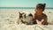 happy affectionate and tender tanned woman in bikini lying on sand at sunny sea beach with her pet, cute welsh corgi dog