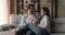 Happy affectionate young family couple drinking coffee resting on sofa.