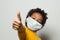 Happy African American black kid in medical protective face mask showing thumb up on white