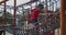 Happy African-American child playing on rope net bridge on outdoor playground.