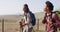 Happy african american couple with backpacks, hiking with trekking poles together, slow motion