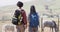 Happy african american couple with backpacks, hiking with trekking poles together, slow motion