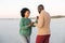 Happy african american couple dancing and smiling on beach at sundown