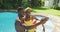 Happy african american couple standing in swimming pool taking selfie and smiling in sunny garden
