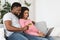 Happy african american expecting family using laptop, shopping online