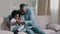 Happy african american family adult funny father playing with daughter sitting on sofa in living room dad tickling