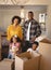 Happy African American family with cardboard boxes looking at camera in living room