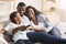 Happy african american family relaxing and watching TV at home