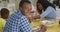 Happy african american father eating lunch with family at home