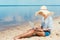 happy african american female freelancer in straw hat sitting on sandy beach