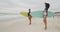 Happy african american female friends on the beach holding surfboards looking toward sea