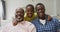 Happy african american grandfather, father and son embracing on sofa