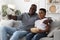 Happy African American Grandfather Watching TV With Grandson At Home Together