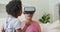 Happy african american grandmother using vr headset with granddaughter in living room