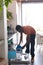 Happy african american man celaning, unloading dishwasher in kitchen