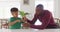 Happy african american man and his son sitting at table and speaking sign language