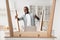 Happy african american man showing thumb up after finishing assembling table by yourself, standing in kitchen interior